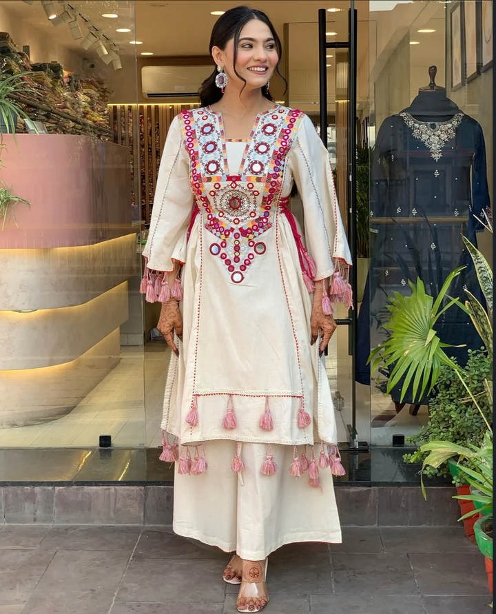 Hand-Embroidered Designer Peplum & Bell Bottom Set with Real Mirror Work Cream Kurta Set with Pink Tassels – Ethnic Festive Wear for Women