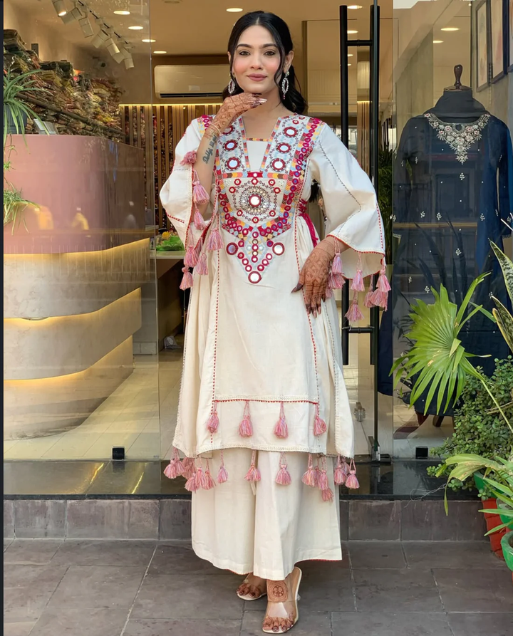 Hand-Embroidered Designer Peplum & Bell Bottom Set with Real Mirror Work Cream Kurta Set with Pink Tassels – Ethnic Festive Wear for Women